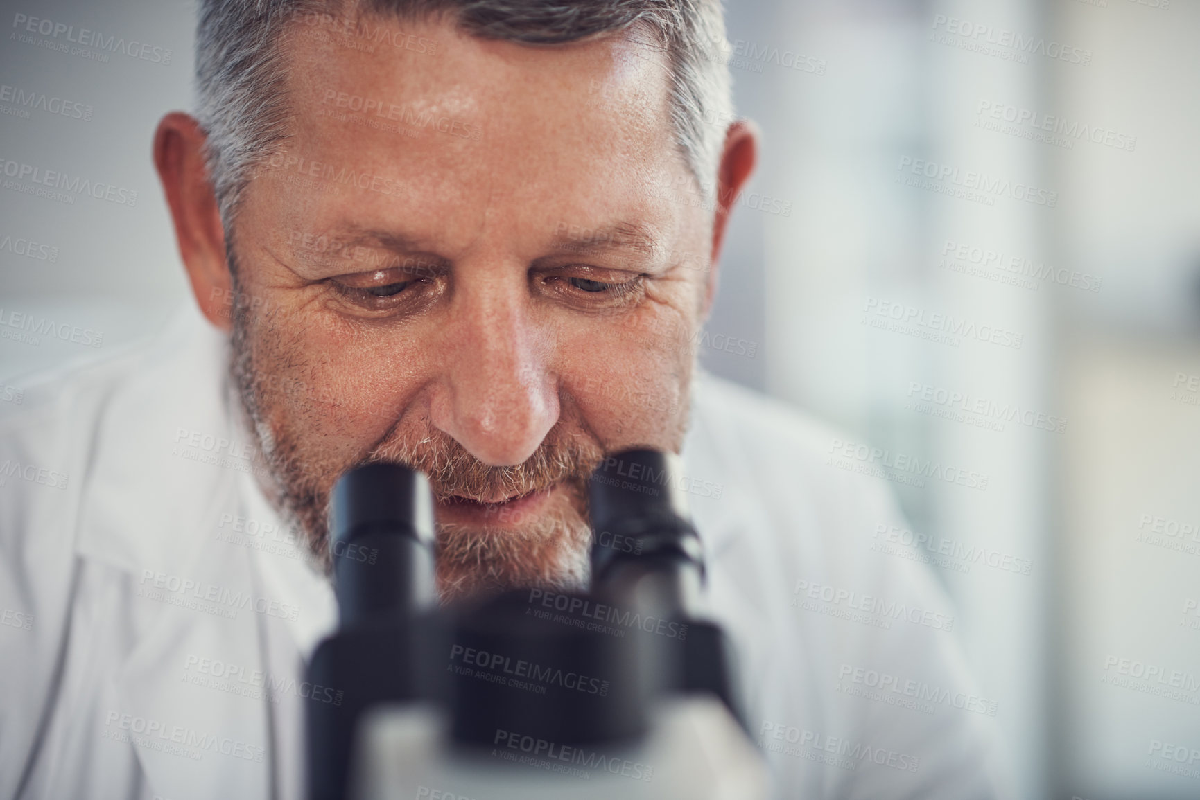 Buy stock photo Shot of a mature scientist using a microscope in a laboratory