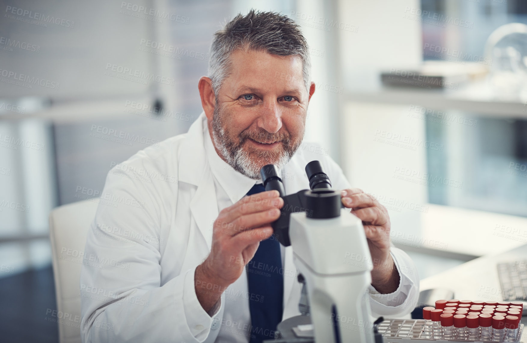 Buy stock photo Portrait of a mature scientist using a microscope in a laboratory