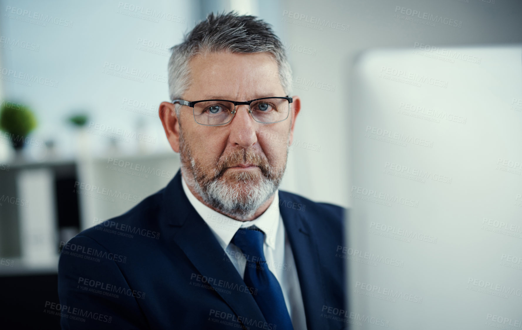 Buy stock photo Portrait of a mature businessman using a computer at his desk in a modern office