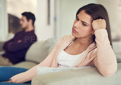 Buy stock photo Shot of a unhappy couple sitting apart from each other on a sofa after a argument at home