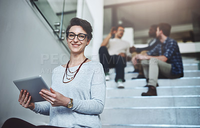 Buy stock photo Portrait of a young designer using a digital tablet with her colleagues in the background