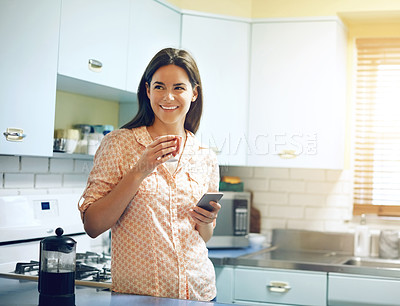 Buy stock photo Shot of an attractive young woman having coffee and using a mobile phone at home