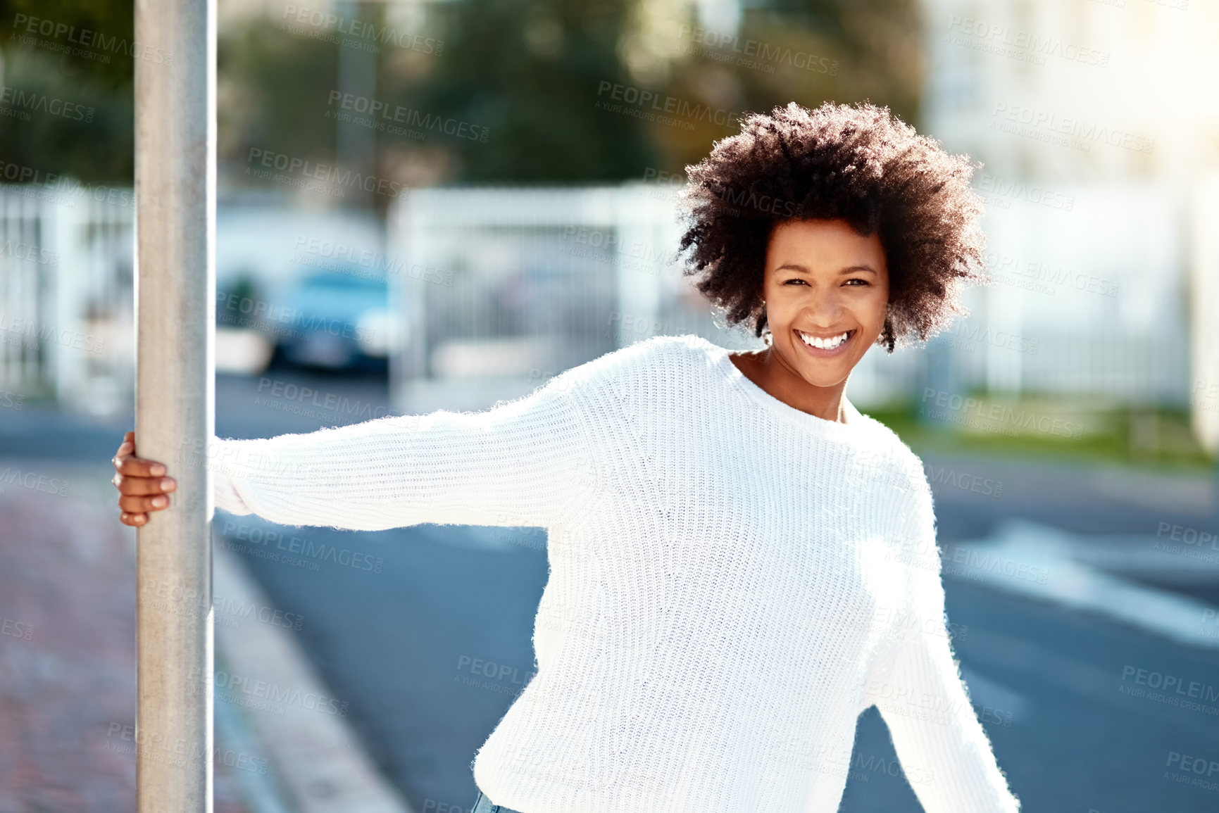 Buy stock photo Happy, black woman and pole in city for portrait with white sweater with fun, carefree and relax by sidewalk. Smile, African and female person as student outside campus to enjoy freedom from lecture
