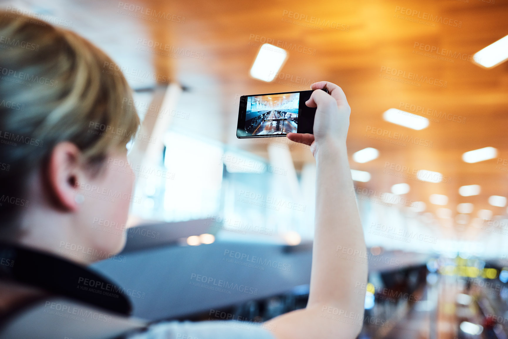 Buy stock photo Shot of an unrecognizable woman taking photos inside an airport 