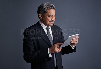 Buy stock photo Studio shot of a mature businessman using his digital tablet