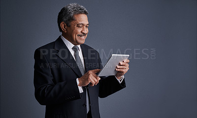 Buy stock photo Studio shot of a mature businessman using his digital tablet