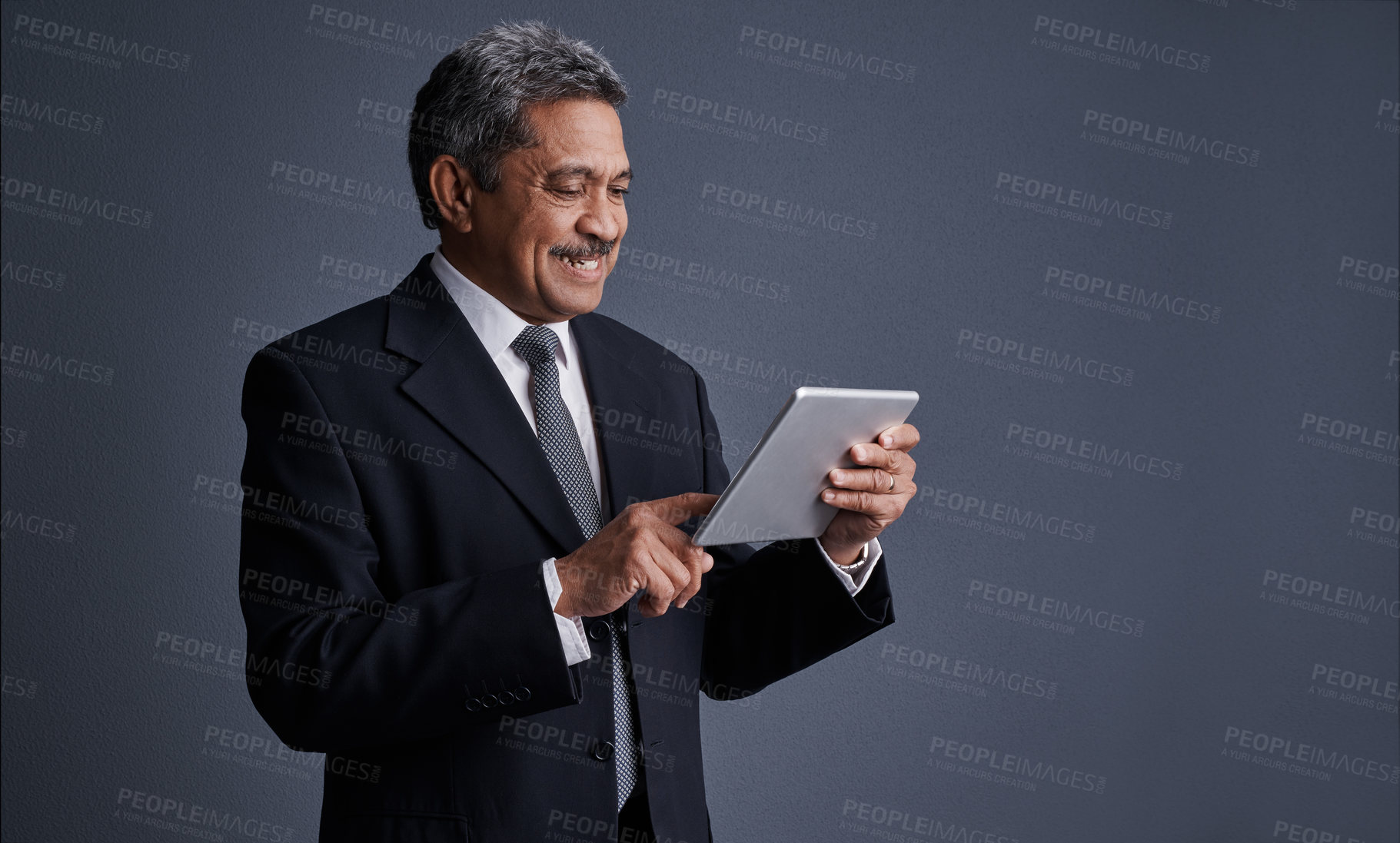 Buy stock photo Studio shot of a mature businessman using his digital tablet