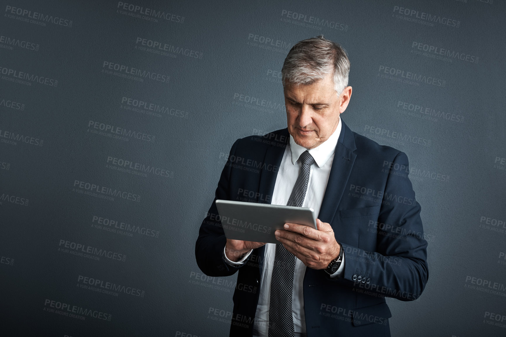 Buy stock photo Studio shot of a mature businessman using his digital tablet