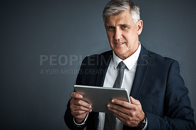 Buy stock photo Studio shot of a mature businessman using his digital tablet