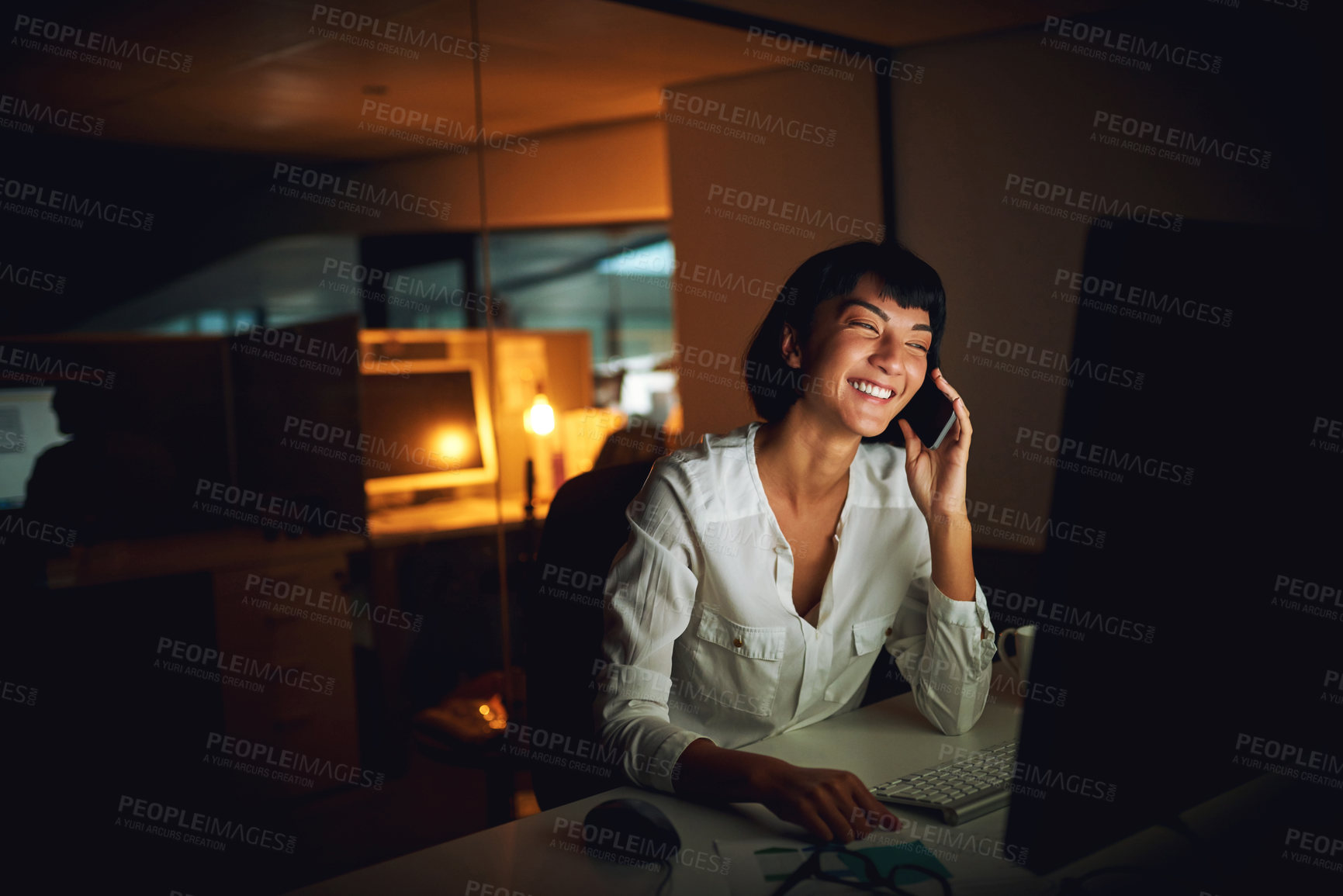 Buy stock photo Shot of a young businesswoman using a mobile phone and computer during a late night at work