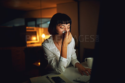 Buy stock photo Shot of a young businesswoman blowing her nose during a late night at work