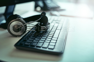 Buy stock photo Closeup shot of a headset lying on a keyboard in an office