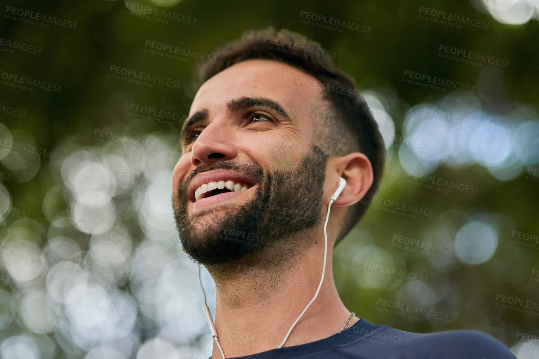 Buy stock photo Thinking, nature and man with earphones for listening to music, podcast or radio with happiness. Fitness, workout and male athlete with audio tech for streaming running playlist at outdoor park.