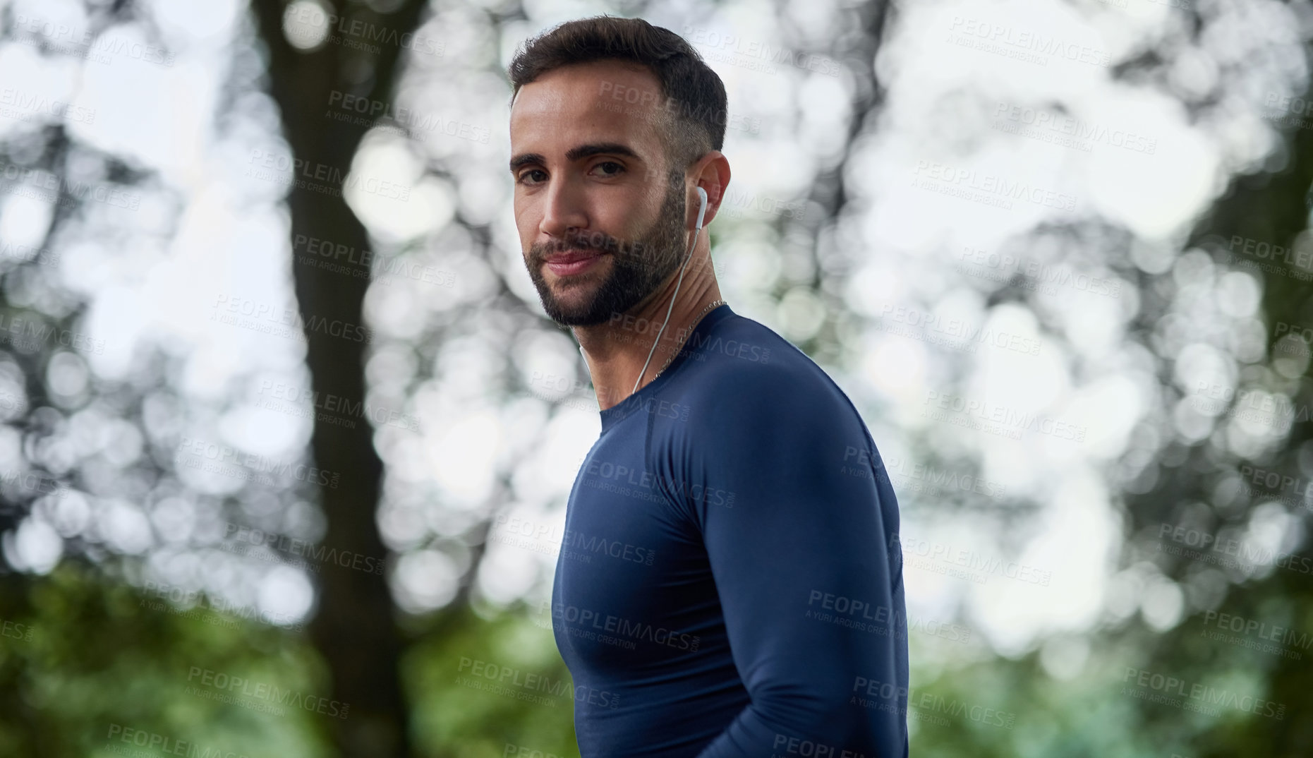 Buy stock photo Cropped portrait of a handsome young male runner listening to music during his workout