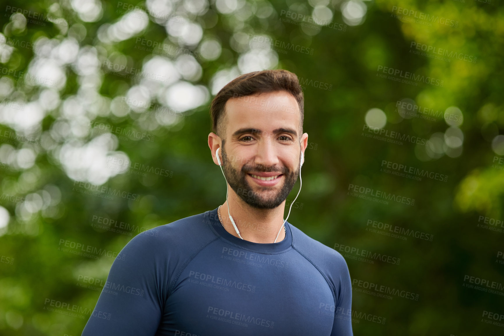 Buy stock photo Cropped portrait of a handsome young male runner listening to music during his workout