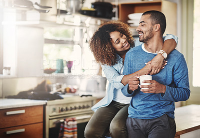 Buy stock photo Romantic loving couple, smiling and enjoying a cup of coffee in the morning together at home in their kitchen. Carefree wife hugging and bonding with husband while relaxing looking in love  