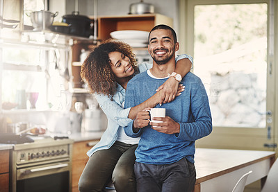 Buy stock photo Happy, hugging and smiling young in love couple bonding in a kitchen at home. Romantic life partners enjoying the morning together feeling relaxed and loving. Portrait of a people embracing romance