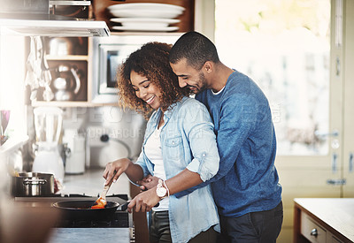 Buy stock photo Loving and affectionate couple cooking breakfast, lunch or dinner together in the kitchen while hugging. Young Black American lovers preparing a meal at home on a fun weekend enjoying quality time