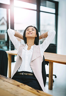 Buy stock photo Cropped shot of an attractive young female designer sitting with her hands behind her head at her desk