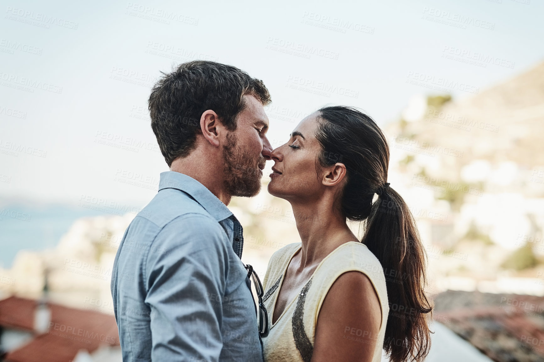 Buy stock photo Couple, romance and rooftop in city on holiday, marriage commitment and travel to Greece. People, outdoor date and support for security in relationship, eskimo kiss and terrace on honeymoon weekend