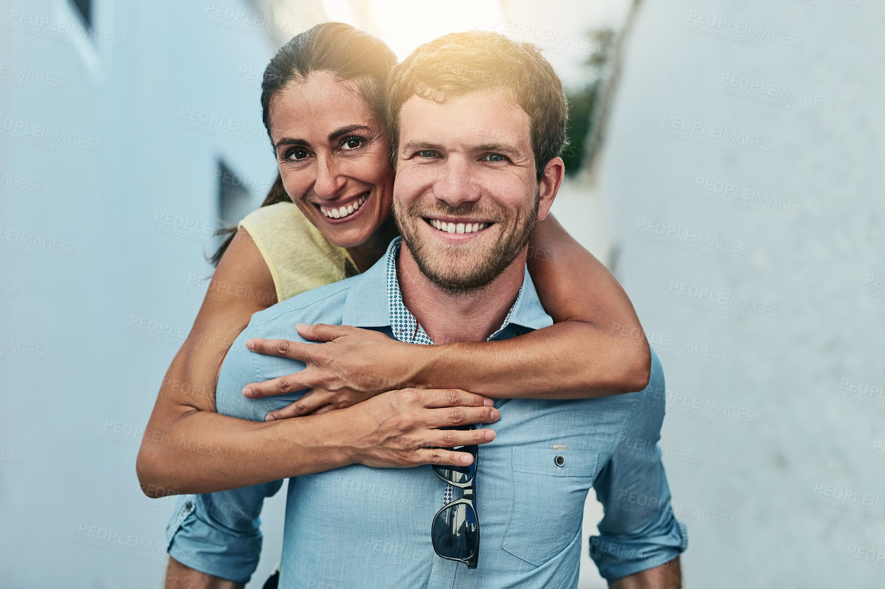 Buy stock photo Couple, portrait and piggyback in town on holiday, marriage commitment and travel to Greece. People, outdoor and support for security in relationship, adventure and play on honeymoon weekend trip