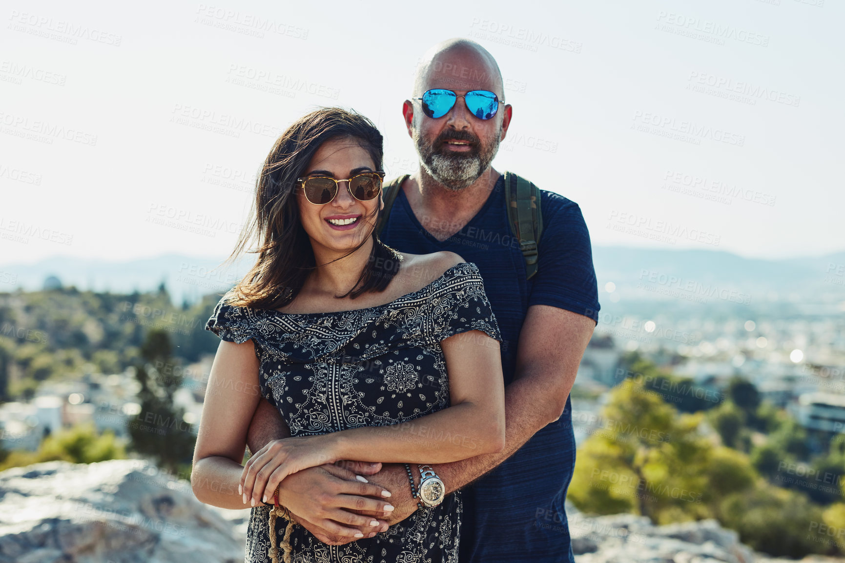 Buy stock photo Outdoor, couple and happy with hug on hill in portrait for fun, bonding and holiday in Spain. People, relationship and smile with sunglasses for summer vacation, travel and break for freedom