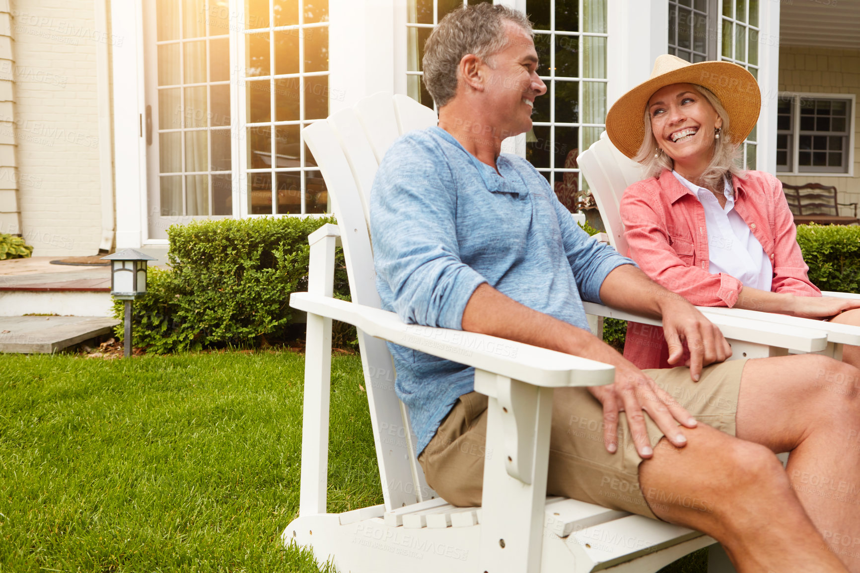 Buy stock photo Mature couple, garden and relax in summer on chair with funny memory, bonding and conversation with love at house. Man, woman and talking with laugh, comic story and chat on grass in home backyard