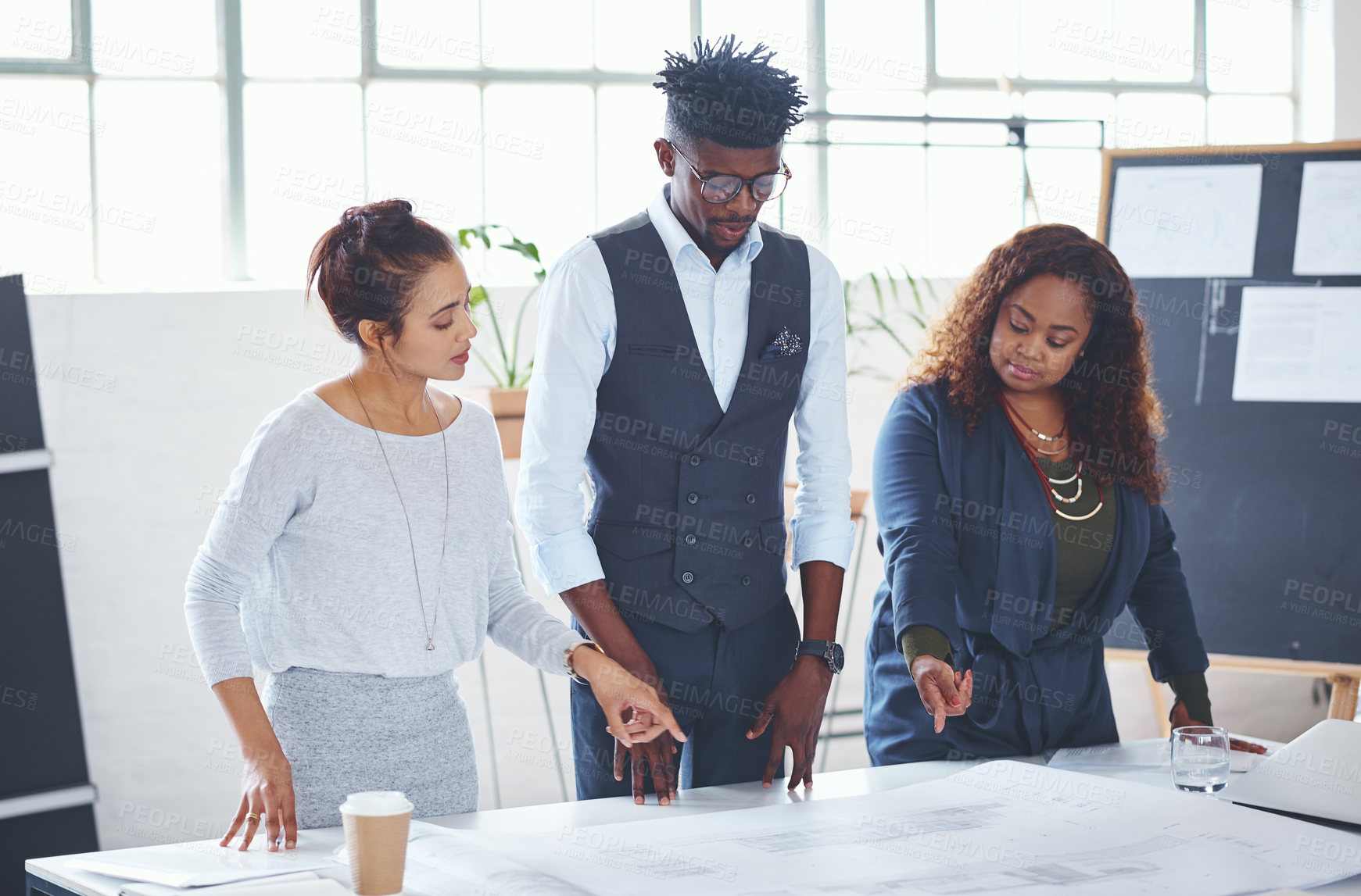 Buy stock photo Cropped shot of a team of professionals working on blueprints in an office