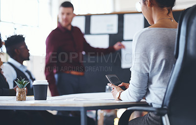 Buy stock photo Shot of a businesswoman texting on her cellphone during a meeting in an office