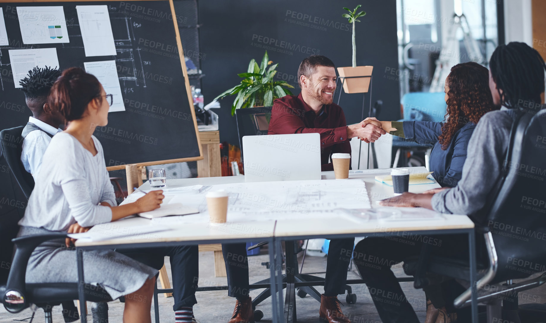 Buy stock photo Cropped shot of two creative businesspeople shaking hands during a meeting in their office