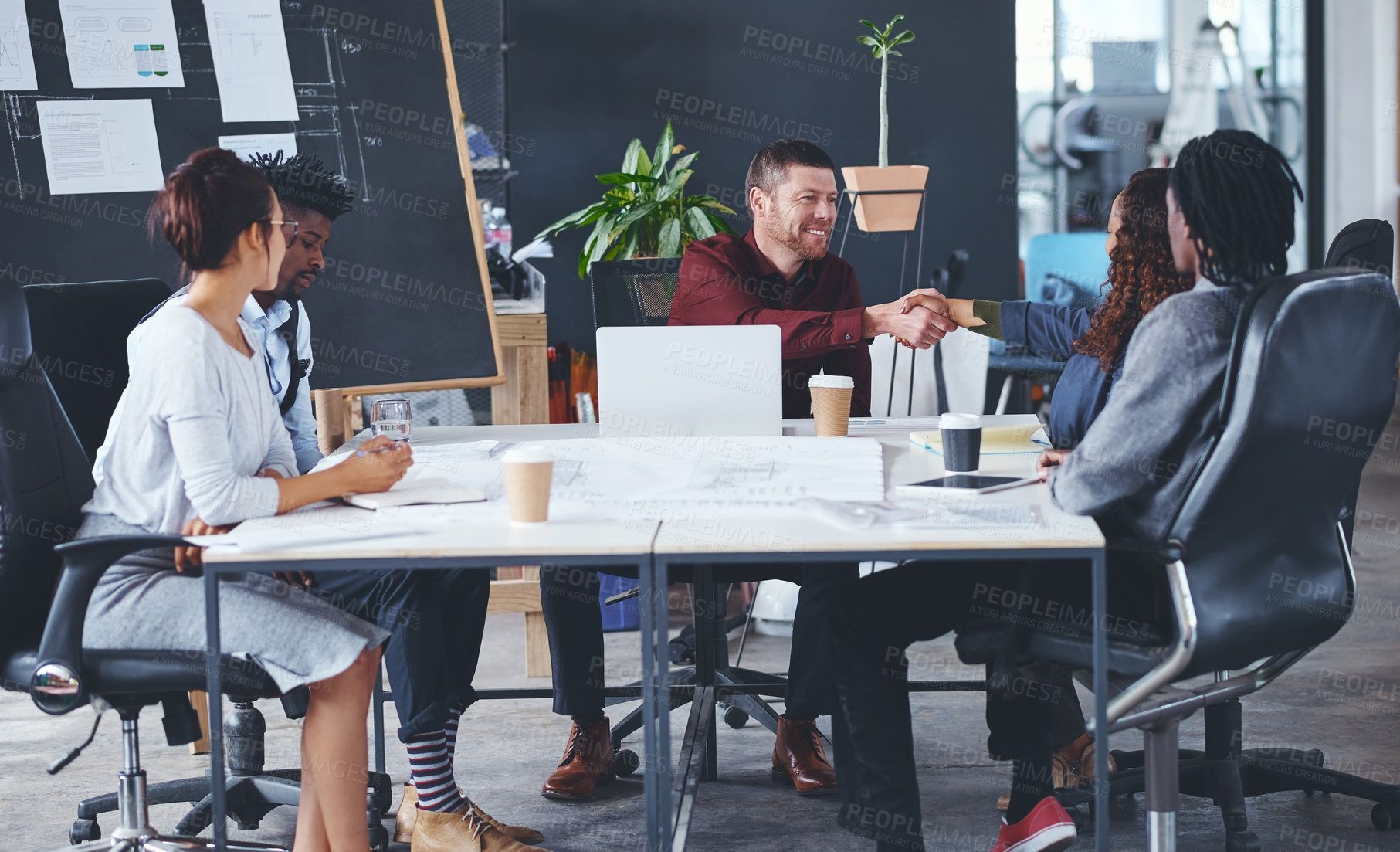 Buy stock photo Cropped shot of two creative businesspeople shaking hands during a meeting in their office