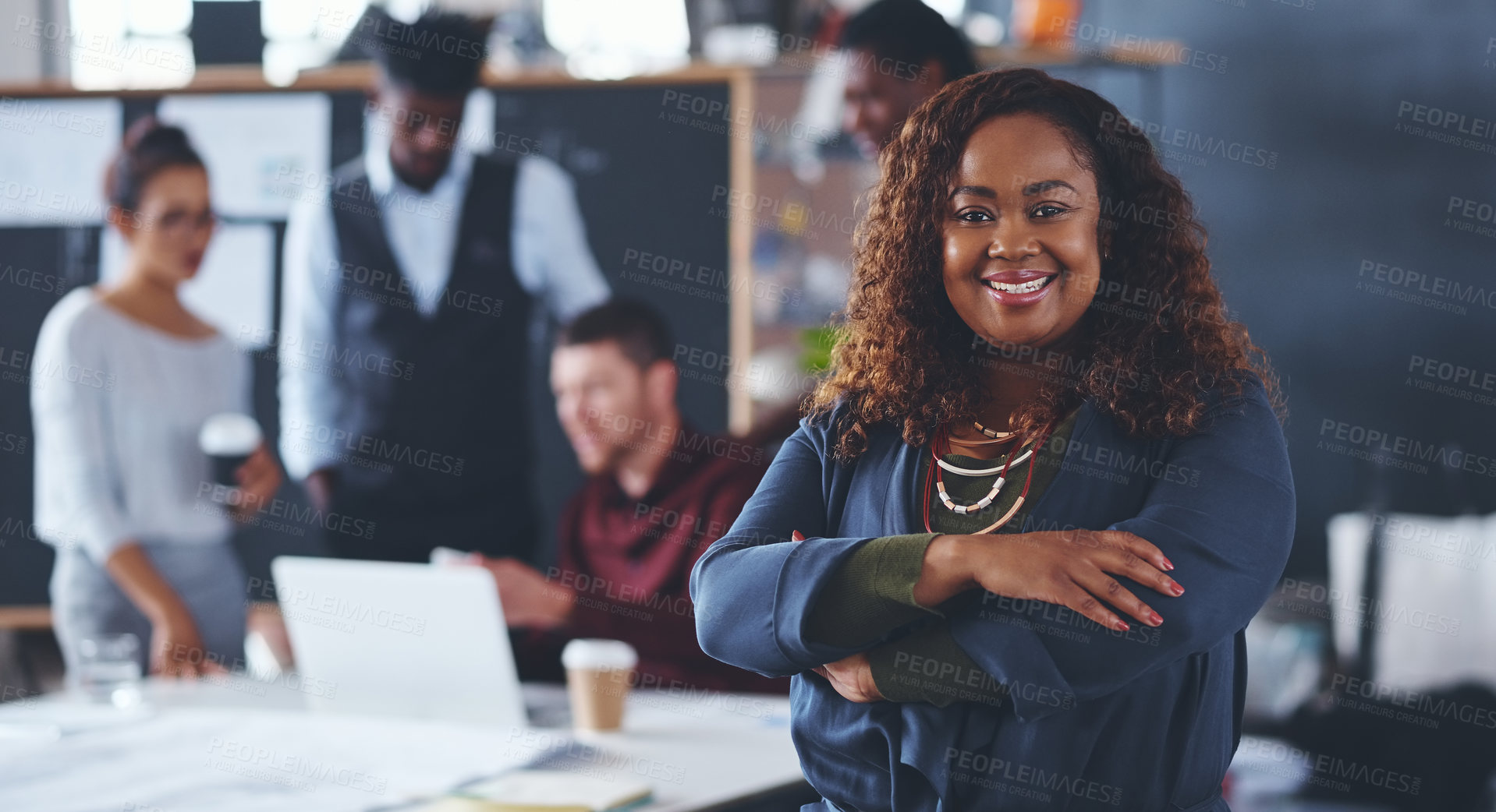 Buy stock photo Cropped portrait of an attractive young businesswoman standing with her arms folded with her colleagues in the background