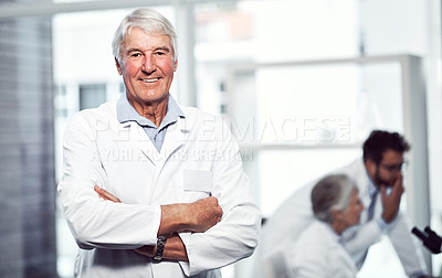 Buy stock photo Portrait of a cheerful elderly male scientist standing with arms folded while looking into the camera inside a laboratory