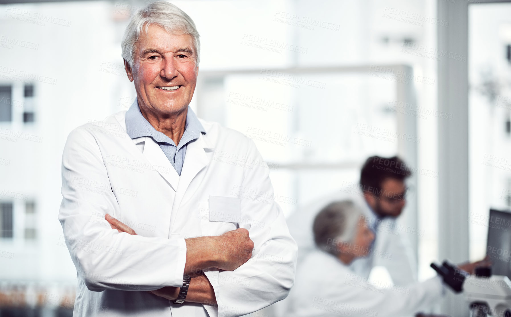 Buy stock photo Portrait of a cheerful elderly male scientist standing with arms folded while looking into the camera inside a laboratory