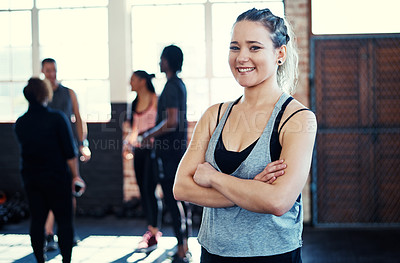 Buy stock photo Portrait of a cheerful young woman standing with her arms folded while looking into the camera before a workout in a gym