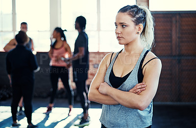 Buy stock photo Shot of a focused young woman standing with arms folded while contemplating before a workout in a gym