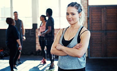 Buy stock photo Portrait of a cheerful young woman standing with her arms folded while looking into the camera before a workout in a gym