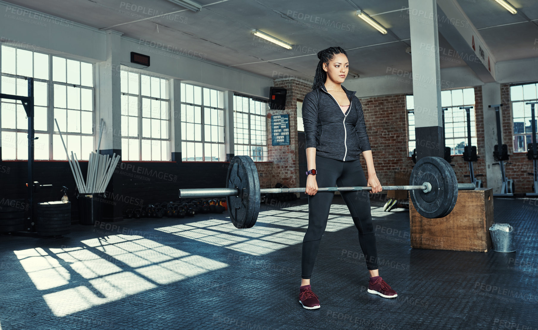 Buy stock photo Shot of a young woman lifting weights in a gym