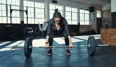 Buy stock photo Shot of a young woman lifting weights in a gym