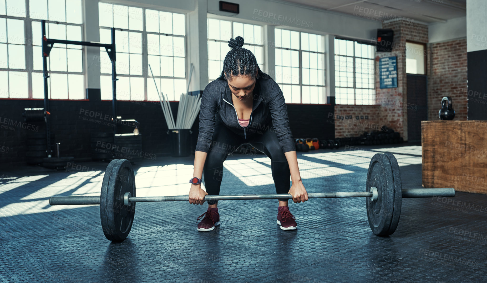 Buy stock photo Shot of a young woman lifting weights in a gym