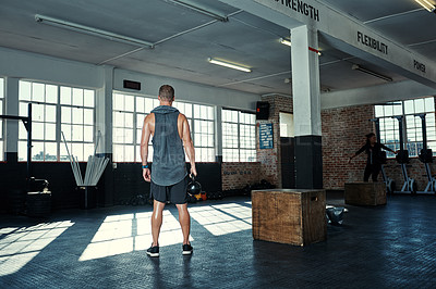 Buy stock photo Rearview shot of an unrecognizable man lifting kettlebells in a gym