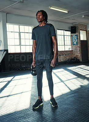 Buy stock photo Shot of a young man lifting kettlebells in a gym