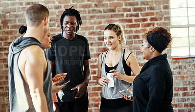 Buy stock photo Shot of a cheerful young group of people standing in a circle and having a conversation before a workout in a gym