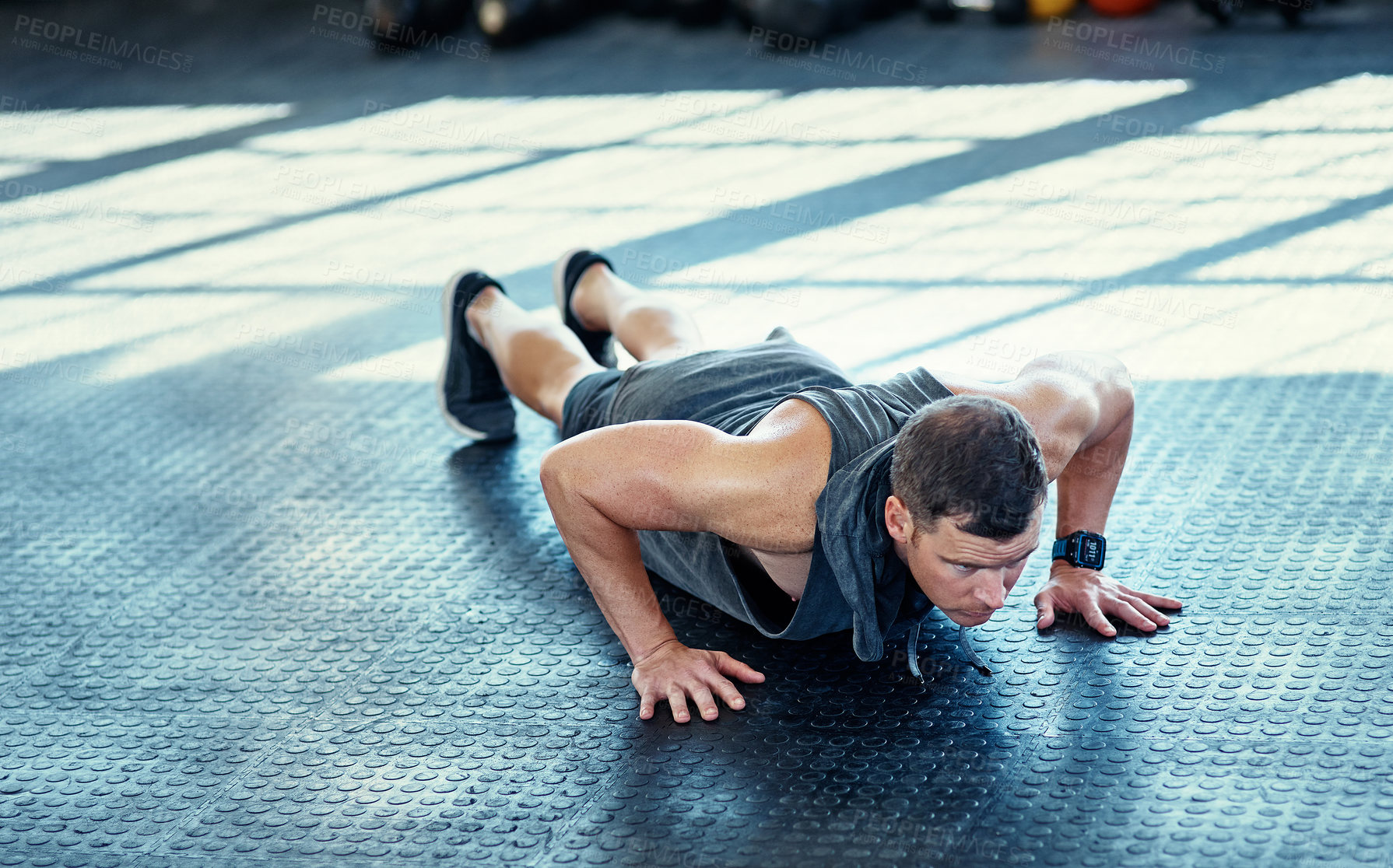 Buy stock photo Shot of a young man doing push ups in a gym