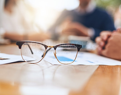 Buy stock photo Shot of a pair of reading glasses on a table in the office