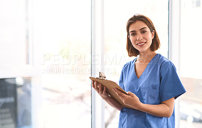 Buy stock photo Portrait of a cheerful young female doctor holding a clipboard while looking at the camera in a clinic