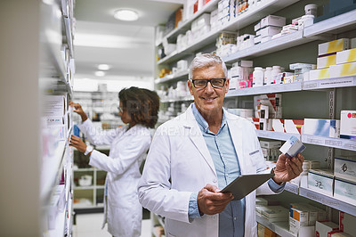 Buy stock photo Portrait of a cheerful mature male pharmacist holding a digital tablet and box of meds while looking at the camera
