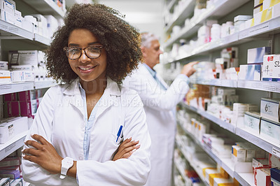 Buy stock photo Portrait of a cheerful young female pharmacist standing with arms folded while looking at the camera in a pharmacy