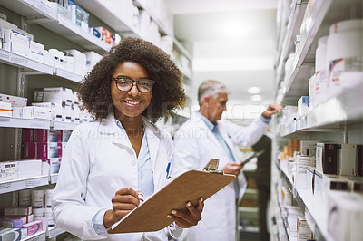 Buy stock photo Portrait of a cheerful young female pharmacist holding a clipboard and doing stock while looking at the camera