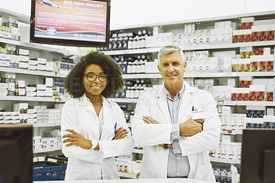 Buy stock photo Portrait of two cheerful and confident pharmacist standing with arms folded while looking into the camera in a pharmacy